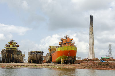 A shipyard beside a brick field, with several large cargo ships and cranes in the background. 