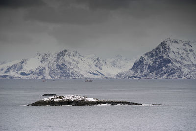 Scenic view of sea and snowcapped mountains against sky