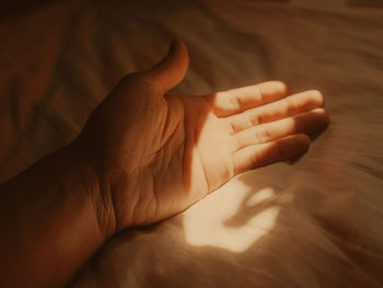 Close-up of person hand on bed