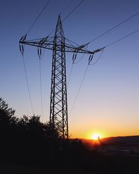 Low angle view of silhouette electricity pylon against sky during sunset