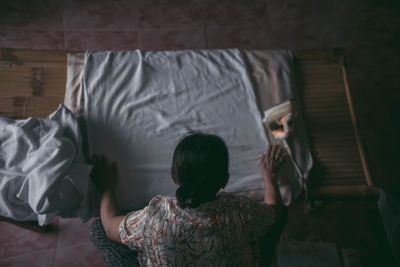 Rear view of women relaxing on bed at home