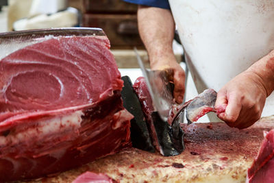  middle section of man cutting tuna