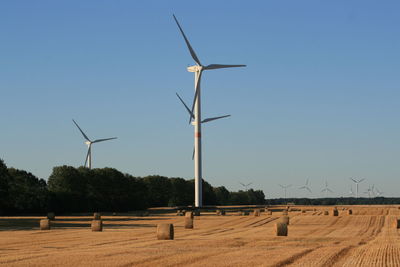 Wind turbines on field against clear sky