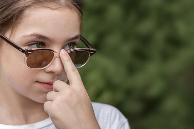 Close-up of a little girl holding sunglasses with her finger and looking into the distance