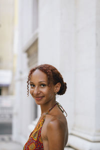 Smiling woman with curly hair standing in front of building