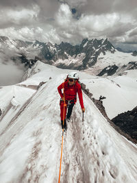 Young female climber on narrow snow ridge above glaciers mt blanc