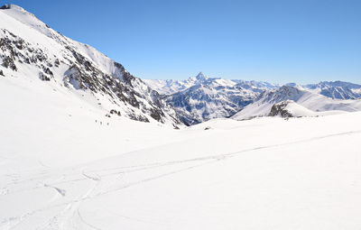 Scenic view of snowcapped mountains against clear blue sky