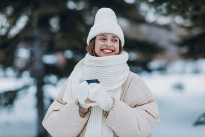 Portrait of smiling young woman standing in snow