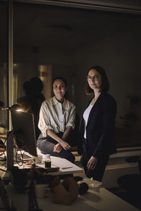 Portrait of multiracial female colleagues in office at night