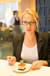 Portrait of smiling woman eating while sitting at restaurant