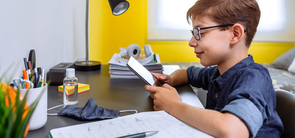 Teenager doing homework with a tablet in his room