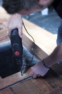 Man drilling in wood at workshop