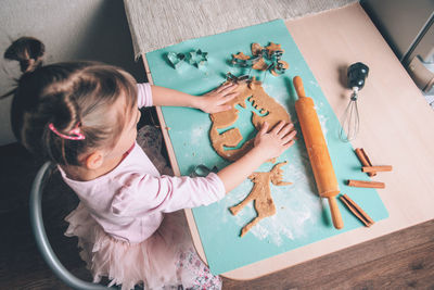 High angle view of cute girl holding table at home