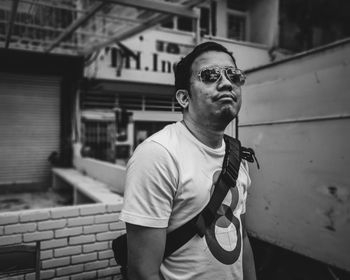 Man wearing sunglasses standing against built structure