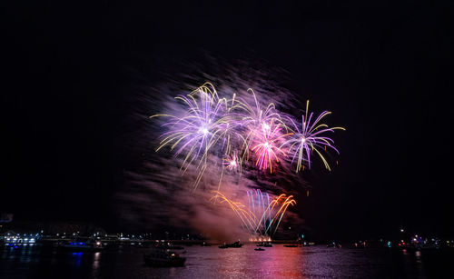 Firework display over river at night