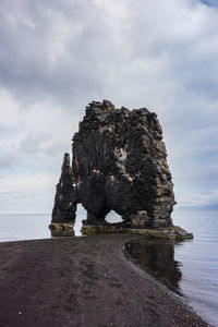 Rock formation on beach against sky