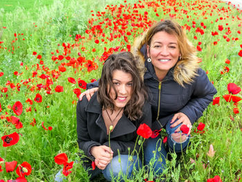 Women around poppy flowers on field