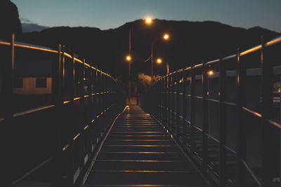 Illuminated footbridge against sky at night