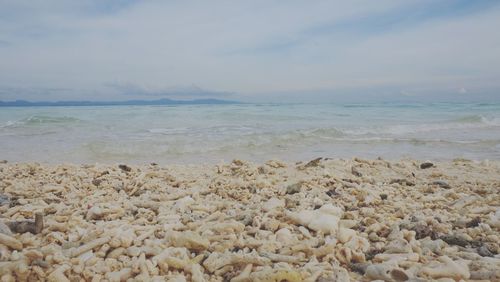 View of calm beach against cloudy sky