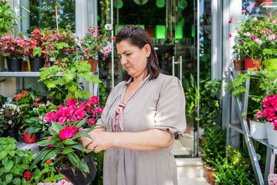 Woman holding potted flower in plant nursery 