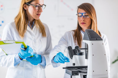 Female scientists examining chemical in laboratory