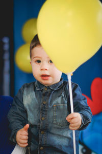 Portrait of cute boy holding yellow balloon