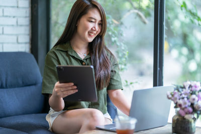 Young woman using phone while sitting at home
