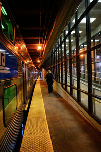 Woman walking on railroad station platform amidst trains