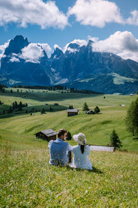 Rear view of people on field by mountain against sky