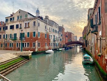 Boats moored in canal amidst buildings in city