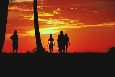 Silhouette men on sidewalk against sky during sunset