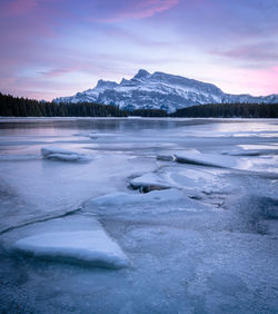 Colorful sunset on frozen lake with isolated mountain in background, two jack lake, banff np, canada