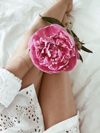 Midsection of woman with bouquet sitting on bed