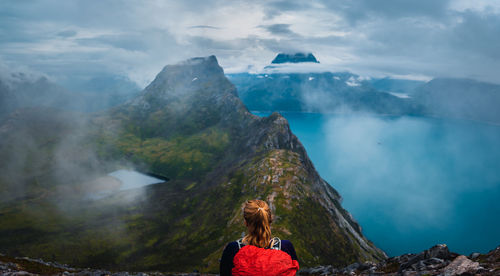 Rear view of woman on rock against sky