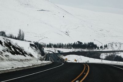 Road by trees against sky during winter