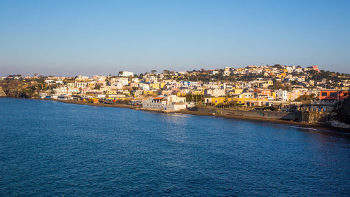 Townscape by sea against clear blue sky