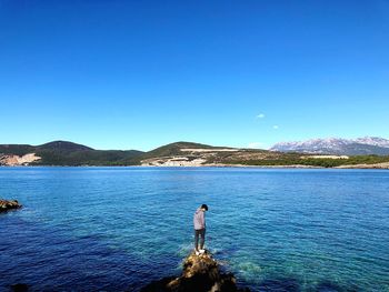 Man standing by sea against blue sky