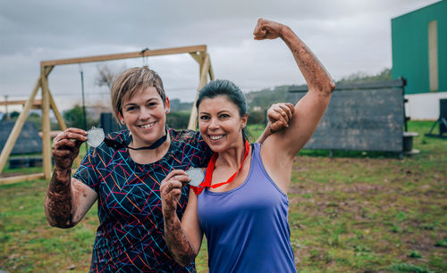 Happy sporty friends showing medals while exercising on land
