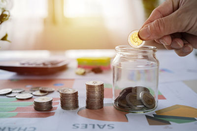 Close-up of hand holding glass jar on table