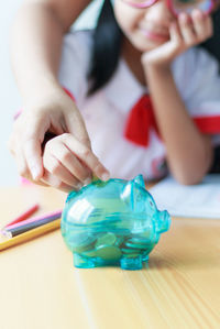 Hands putting coin in piggy bank