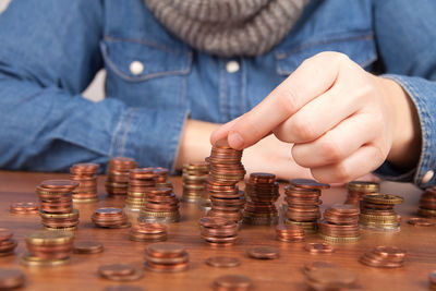 Midsection of woman stacking coins at table