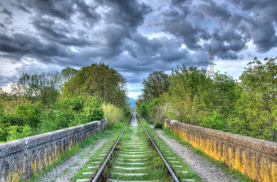 Railroad track against cloudy sky