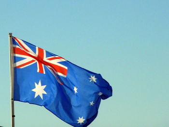 Low angle view of flag against clear blue sky