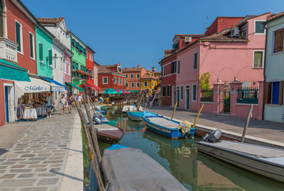 Boats moored on canal amidst buildings in city