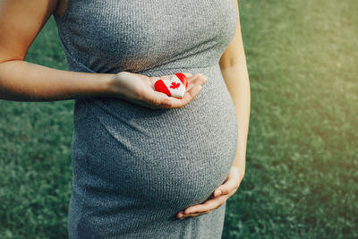 Midsection of woman holding red while standing on field