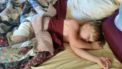 High angle view of boy sleeping on bed at home