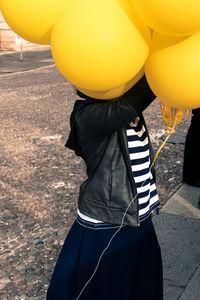 Girl with yellow balloons on footpath in city