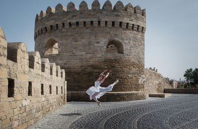 Woman jumping on road against historic building 
