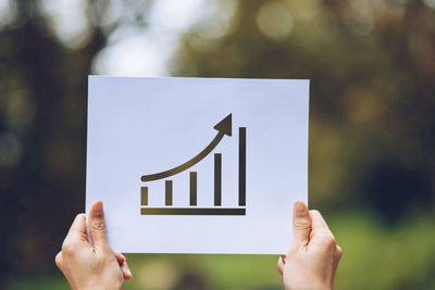 Close-up of hand holding text against blurred background