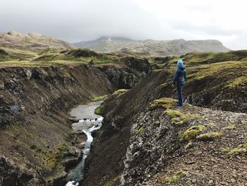 Rear view of person on rocks against mountains